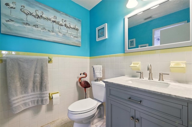 3020 E Scofield St, Inverness, FL 34453 - bathroom with toilet, vanity, speckle patterned floor, and tile walls