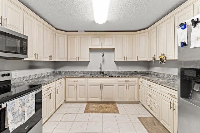 7059 N Lecanto Hwy, Hernando, FL 34442 - kitchen featuring stainless steel appliances, a sink, a textured ceiling, cream cabinetry, and dark stone counters
