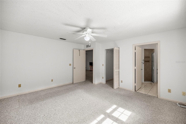 9667 SW 94th Ct Unit C, Ocala, FL 34481 - unfurnished bedroom with light colored carpet, a textured ceiling, ensuite bathroom, baseboards, and a ceiling fan
