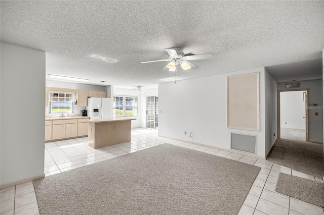 9667 SW 94th Ct Unit C, Ocala, FL 34481 - kitchen with white refrigerator with ice dispenser, light tile patterned floors, a kitchen island, a sink, and a textured ceiling