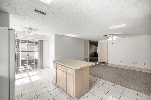 9667 SW 94th Ct Unit C, Ocala, FL 34481 - kitchen with freestanding refrigerator, ceiling fan, light tile patterned floors, a kitchen island, and a textured ceiling