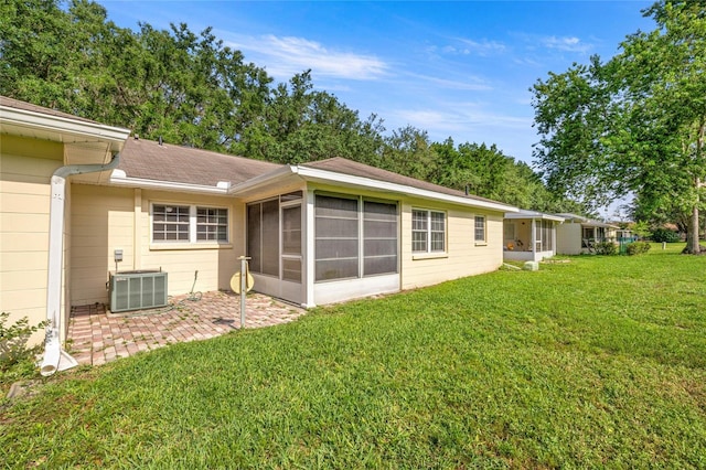 9667 SW 94th Ct Unit C, Ocala, FL 34481 - back of property featuring a sunroom, central AC, a lawn, a patio area, and a shingled roof