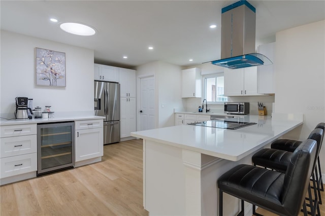 8622 Baylor Cir, Orlando, FL 32817 - kitchen featuring wine cooler, stainless steel appliances, island exhaust hood, a breakfast bar area, and white cabinetry
