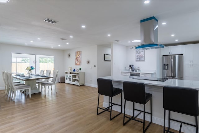 8622 Baylor Cir, Orlando, FL 32817 - kitchen featuring stainless steel fridge with ice dispenser, island exhaust hood, light countertops, a breakfast bar, and light wood-type flooring