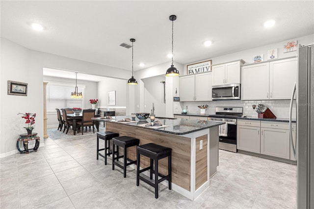 7641 SW 63rd Lane Rd, Ocala, FL 34474 - kitchen featuring appliances with stainless steel finishes, backsplash, a kitchen bar, a kitchen island with sink, and dark stone countertops