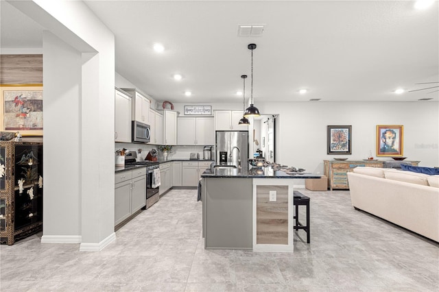 7641 SW 63rd Lane Rd, Ocala, FL 34474 - kitchen featuring appliances with stainless steel finishes, a kitchen bar, open floor plan, decorative light fixtures, and a center island with sink