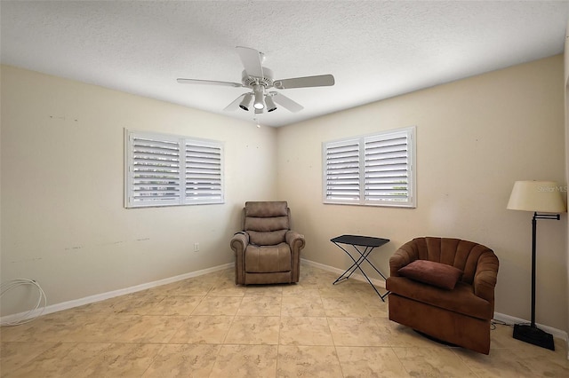 sitting room featuring ceiling fan, baseboards, and a textured ceiling