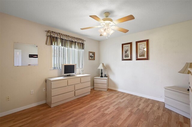 bedroom featuring light wood-style flooring, baseboards, a desk, and ceiling fan