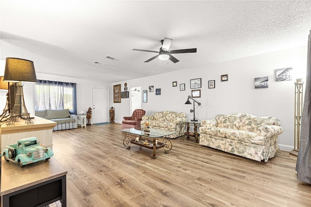 living area featuring a ceiling fan, light wood finished floors, and a textured ceiling