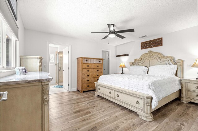 bedroom with light wood finished floors, a textured ceiling, a ceiling fan, and connected bathroom