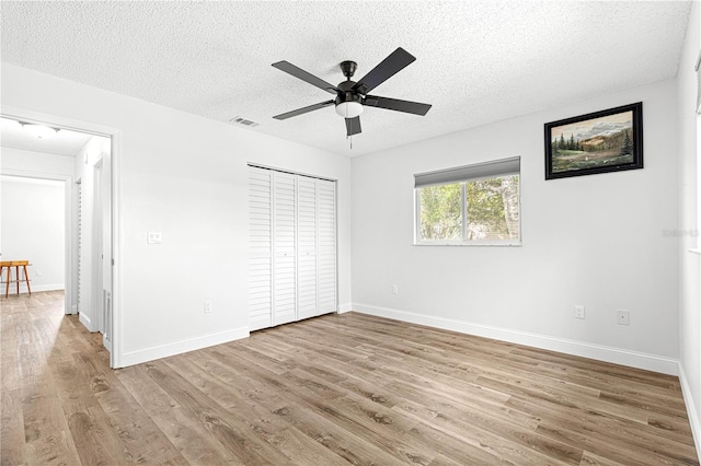 unfurnished bedroom featuring a textured ceiling, wood finished floors, baseboards, a closet, and ceiling fan