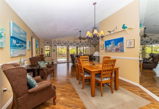 dining area featuring a ceiling fan, vaulted ceiling, wood finished floors, a chandelier, and baseboards