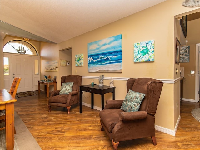living area featuring wood finished floors, lofted ceiling, and baseboards