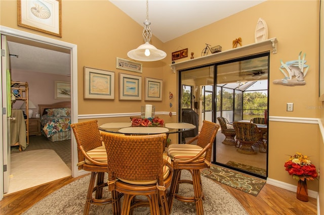 dining room with wood finished floors, lofted ceiling, baseboards, and a sunroom