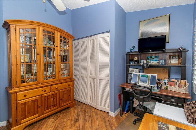 office space featuring wood finished floors, baseboards, and ceiling fan