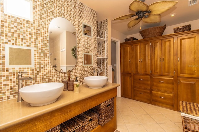 full bath with backsplash, tile patterned floors, a ceiling fan, double vanity, and tile walls