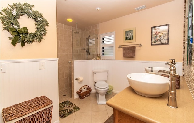 bathroom featuring a wainscoted wall, tile patterned floors, a walk in shower, toilet, and vanity
