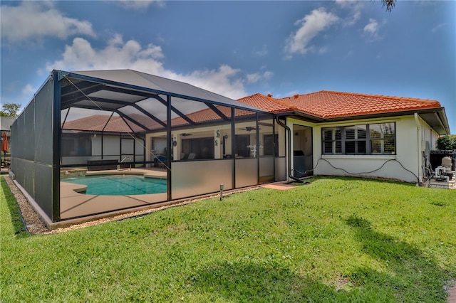 back of house featuring a tiled roof, an outdoor pool, a ceiling fan, a yard, and a patio