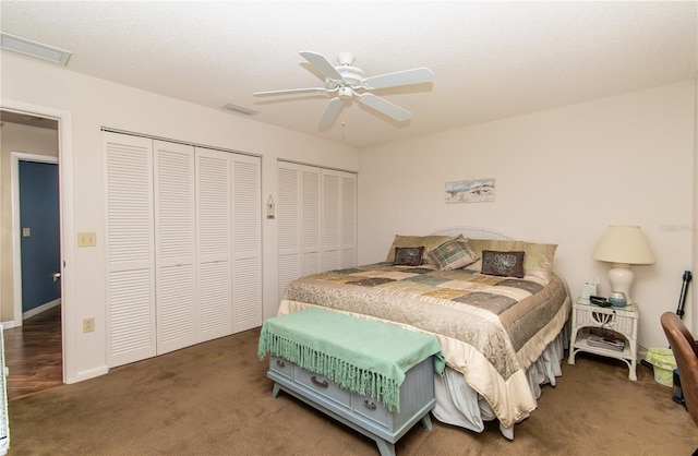 carpeted bedroom with two closets, ceiling fan, and baseboards