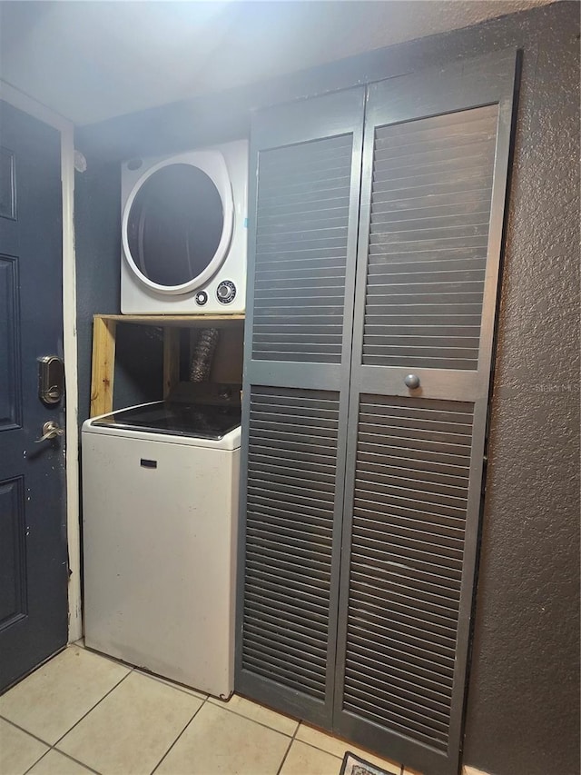 1810 NW 23rd Blvd Unit 230A, Gainesville, FL 32605 - washroom featuring stacked washer and clothes dryer and light tile patterned floors