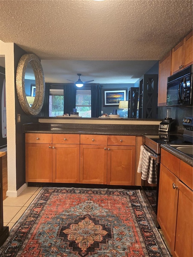 1810 NW 23rd Blvd Unit 230A, Gainesville, FL 32605 - kitchen with black microwave, stainless steel electric range, a textured ceiling, brown cabinets, and a ceiling fan