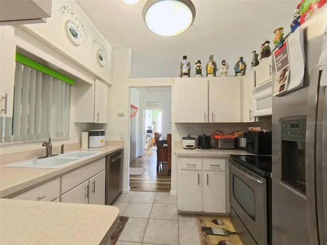 5340 NW 26th Ln, Ocala, FL 34482 - kitchen with appliances with stainless steel finishes, a sink, light tile patterned floors, light countertops, and white cabinets