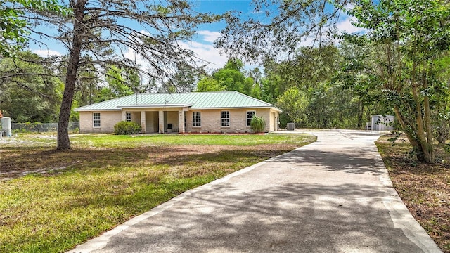 single story home with stone siding, concrete driveway, and metal roof