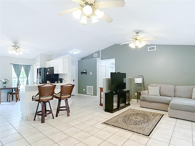 living area with lofted ceiling, a ceiling fan, light tile patterned flooring, and baseboards