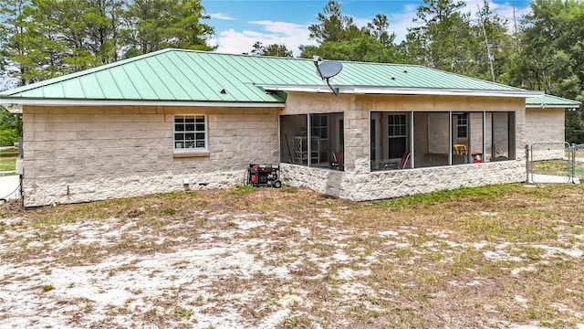 rear view of house featuring a sunroom, metal roof, a standing seam roof, and a gate