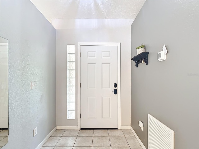 foyer with light tile patterned flooring, baseboards, and a textured ceiling