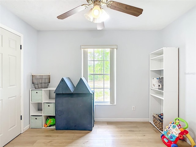 playroom featuring wood finished floors, ceiling fan, and baseboards