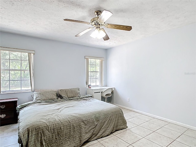 bedroom featuring a textured ceiling, light tile patterned floors, baseboards, and ceiling fan