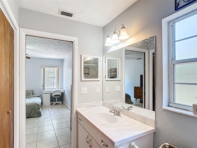 ensuite bathroom featuring a textured ceiling, tile patterned flooring, vanity, baseboards, and a textured wall