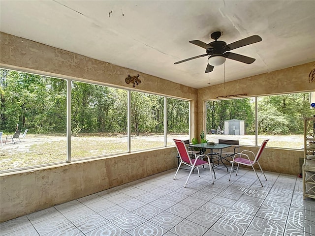 sunroom / solarium with healthy amount of natural light, outdoor dining area, and a ceiling fan