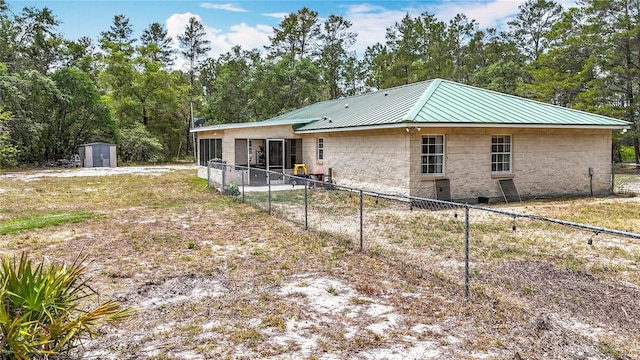 rear view of house featuring a shed, fence, metal roof, and an outdoor structure