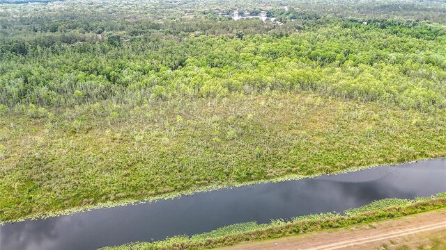 drone / aerial view of a heavily wooded area and a nearby body of water