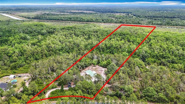 aerial view of property and surrounding area with a forest and property parcel outlined