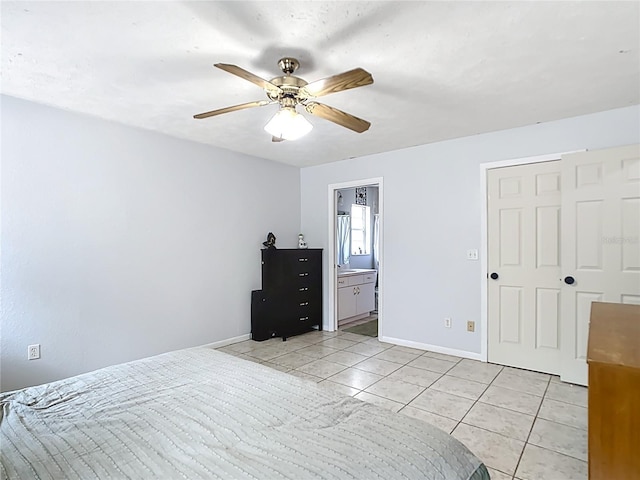 bedroom featuring light tile patterned floors, baseboards, a ceiling fan, and ensuite bath
