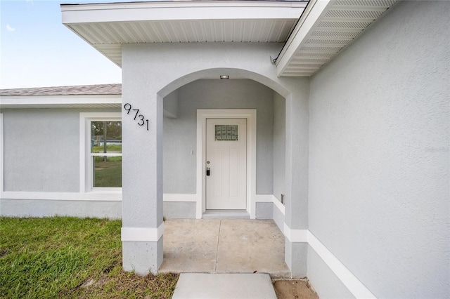 9731 Bahia Rd, Ocala, FL 34472 - view of exterior entry featuring stucco siding and a shingled roof