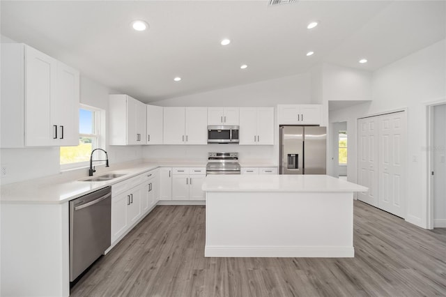 9731 Bahia Rd, Ocala, FL 34472 - kitchen with appliances with stainless steel finishes, a sink, a kitchen island, white cabinetry, and light wood-type flooring