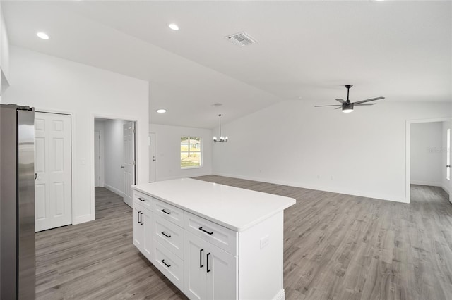 9731 Bahia Rd, Ocala, FL 34472 - kitchen with freestanding refrigerator, light wood-style floors, ceiling fan, white cabinetry, and vaulted ceiling