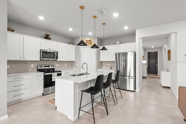 9459 SW 52nd Loop, Ocala, FL 34481 - kitchen featuring stainless steel appliances, decorative backsplash, a kitchen island with sink, white cabinetry, and light countertops