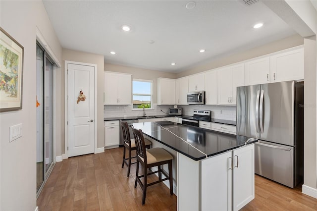 8820 SW 58th Street Rd, Ocala, FL 34481 - kitchen with appliances with stainless steel finishes, dark countertops, tasteful backsplash, light wood-style flooring, and white cabinetry