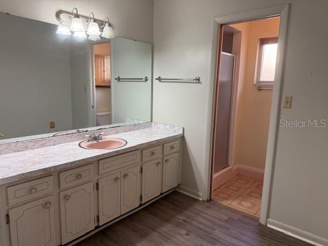 616 Water Rd, Ocala, FL 34472 - full bath with vanity, a stall shower, wood finished floors, and baseboards