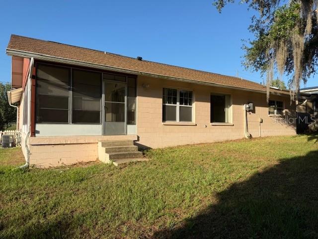 616 Water Rd, Ocala, FL 34472 - rear view of house with concrete block siding, entry steps, a lawn, and roof with shingles