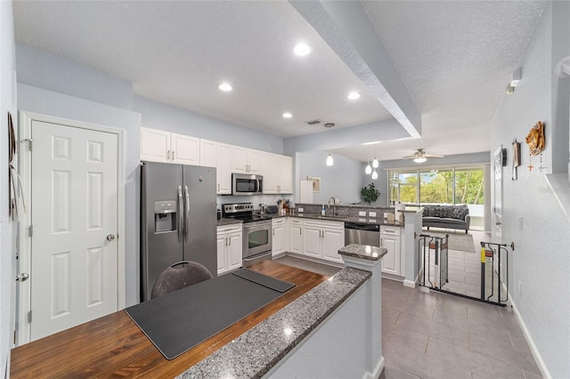 4927 SW 45th Cir, Ocala, FL 34474 - kitchen featuring appliances with stainless steel finishes, a peninsula, white cabinetry, ceiling fan, and dark stone counters