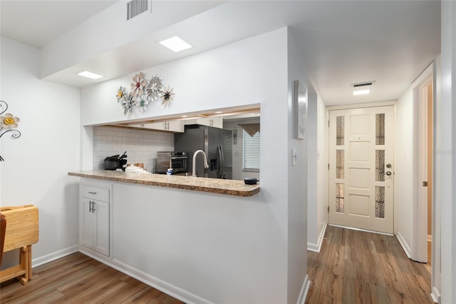 3815 NE 17th Street Cir, Ocala, FL 34470 - kitchen featuring stainless steel fridge with ice dispenser, wood finished floors, decorative backsplash, light countertops, and baseboards