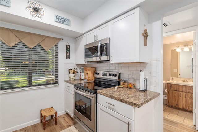 3815 NE 17th Street Cir, Ocala, FL 34470 - kitchen featuring appliances with stainless steel finishes, backsplash, light wood-style floors, white cabinets, and a sink