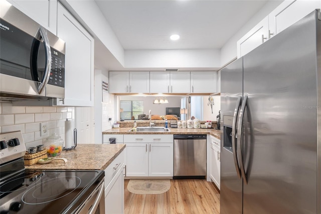 3815 NE 17th Street Cir, Ocala, FL 34470 - kitchen featuring stainless steel appliances, a sink, white cabinetry, light wood finished floors, and decorative backsplash