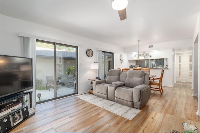 3815 NE 17th Street Cir, Ocala, FL 34470 - living room with ceiling fan, light wood finished floors, baseboards, and a chandelier
